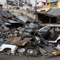 An Indian worker dismantles an old car amid heaps of scrap April 23 in Bangalore, India. Climate change could push more than 100 million people into extreme poverty by 2030 by disrupting agriculture and fueling the spread of malaria and other diseases, the World Bank said in a report Sunday. World Bank warns global warming may put 100 million more people in poverty