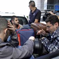 Syrian men sit in the bed of a truck after being detained at Toncontin international airport in Tegucigalpa Wednesday. Honduran authorities have detained five Syrian nationals who were trying to reach the United States using stolen Greek passports, but there are no signs of any links to last week's attacks in Paris, police said. Syrians, with smugglers' help, fleeing war via Latin America, many on forged Greek passports