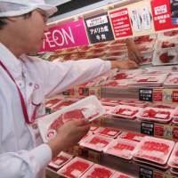 A shop assistant displays American beef at an Aeon supermarket in Tokyo in this file image from 2008. Reductions in beef tariffs under the Trans-Pacific Partnership may bring down prices across the domestic beef market. TPP no done deal; hurdles include interpretation, legislative approval, U.S. election