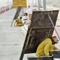 Too hot to handle: A laborer avoids the sun by hiding behind a wooden sign as he works on a manhole alongside of a road that is under construction in Dubai. Persian Gulf could be too hot for humans by 2100
