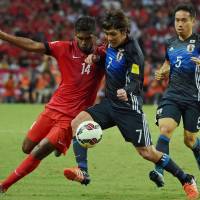 Singapore's Hariss Harun (left) and Japan's Yosuke Kashiwagi vie for the ball as Yuto Nagatomo watches during their second-round Asian qualifier in Singapore on Thursday. Japan defeated Singapore 3-0. Japan trounces Singapore in World Cup qualifier