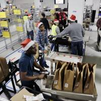 Amazon Prime employees push carts with bags loaded with goods for delivery to customers at the company's urban fulfillment facility Dec. 22 in New York. Online consumer boom sets Amazon holiday shipping, Christmas Eve delivery record