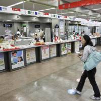 Employees work at banking and insurance counters at a Japan Post Co. post office in Tokyo in October. Government panel recommends increase in Japan Post Bank deposit cap