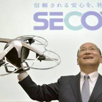 Hiroshi Ito, president of security company Secom Co., holds up a drone during a news conference in Tokyo on Thursday. Secom to start security service using drones on Friday