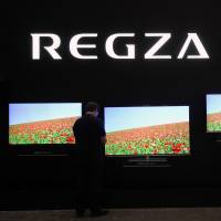 An attendee of CEATEC Japan 2012 looks at Toshiba's Regza 4K LCD televisions. Toshiba to end TV production, shrink staff, sell assembly plants overseas