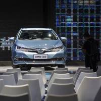An attendee stands near a Toyota Motor Corp. Corolla hybrid at the International Automobile Exhibition in Guangzhou, China, in November. Chinese cities give Toyota boost in hunt for hybrid car buyers