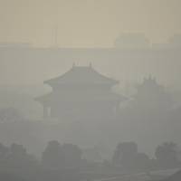 Buildings standing inside the Forbidden City in central Beijing are seen through smog after a red alert for air pollution was issued on Saturday. Beijing issues second red alert after choking smog smothers capital
