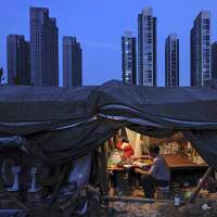 A Chinese laborer eats dinner in his shed at a construction site for a residential complex in Hefei, Anhui province, in this file photo. China eyes huge deficit to cushion reforms, slowing growth