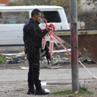 An Israeli security forces member collects cordon tape at the site of an attack near the Israeli settlement of Kiryat Arba outside the flash-point city of Hebron in the occupied West Bank, on Sunday. Israeli cop quizzed over fatal shooting of Palestinian knife attacker, 16, wounding of accomplice, 14