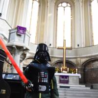 A person with a lightsaber stands in front of the altar inside the Zion Church in Berlin on Sunday ahead of a “Star Wars”-themed church service. The event was held three days after the film “Star Wars: The Force Awakens,” had its world premiere. Pastors at Berlin church carry lightsabers during 'Star Wars'-themed service