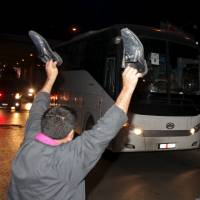 A man holds up his shoes as a bus carrying rebel fighters from the besieged rebel-held Syrian town of Zabadani heads toward Beirut international airport for the fighters to board a plane to Turkey on Monday. Homs blasts claim 19 as Syria rebels, civilians begin rare, U.N.-backed evacuation