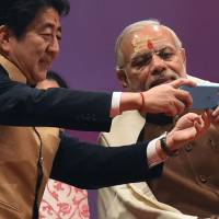 Prime Minister Shinzo Abe and Indian Prime Minister Narendra Modi take a photo together on a mobile phone on the banks of the River Ganges in Varanasi, India, on Saturday. Abe-Modi deals shows Asia's top powers moving to keep rising China in check
