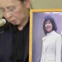 A portrait of Mina Mori, a former employee of major pub chain Watami who committed suicide in 2008, is seen at a Tokyo news conference Tuesday afternoon, as her mother, Yuko, looks on. Mori’s family and Watami reached an out-of-court settlement earlier Tuesday, in which the pub chain founded by Upper House member Miki Watanabe acknowledged that Mori died from overwork and agreed to pay ¥130 million in compensation. Pub chain Watami, founder settle suit over suicide of overworked staffer