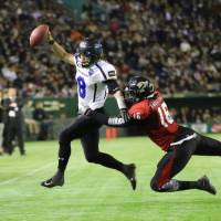 Panasonic Impulse quarterback Tetsuo Takata rushes as Fujitsu Frontiers linebacker Trasaun Nixon attempts to tackle him during the Japan X Bowl at Tokyo Dome on Monday. Impulse down Frontiers to win Japan X Bowl