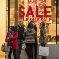 Shoppers stand outside a Uniqlo Co. store in downtown San Francisco in late December. Warm winter means damp profits for Fast Retailing