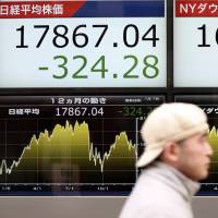 A pedestrian passes a board displaying the Nikkei and Dow Jones Industrial Average outside a securities firm in the capital on Thursday. Stocks in Tokyo hit their lowest levels since Oct. 2. Nikkei hits three-month low; China stocks plunge before trading halted