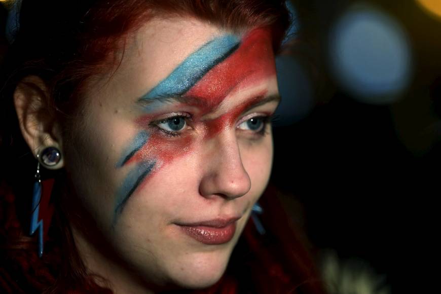 A fan of David Bowie joins other revellers in London to celebrate the life of the musician after the announcement of his death on Jan. 11. Fans gather online to pay tribute to the many faces of David Bowie