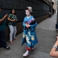Tourists snap photographs of a maiko, or apprentice geisha, walking through the Gion area of Kyoto in May. Visitors to Japan surge to record 19.73 million, spend all-time high ¥3.48 trillion