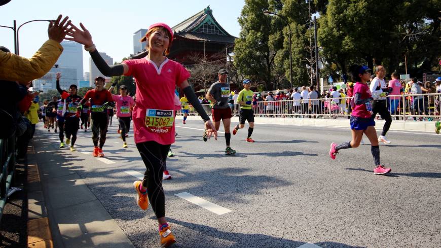 A Tokyo Marathon runner gets a high five of supporter near Zojo-ji Temple in Tokyo on Sunday.