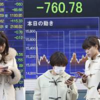 People pause in front of a stock price display showing the Nikkei's first close below 15,000 in 16 months. Abenomics on ropes as reform arrow, BOJ 'bazooka' misfire