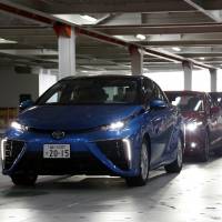 A Toyota Motor Corp. Mirai fuel-cell vehicle (left) is seen aboard a car transporter at Osanbashi Yokohama International Passenger Terminal in Yokohama on Friday. The ship, the Drive Green Highway, is operated by Kawasaki Kisen Kaisha Ltd. Strong yen is a brake on Japanese carmakers' profits
