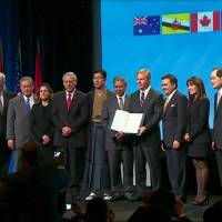 New Zealand Prime Minister John Key (holding agreement), Senior Vice Minister of the Cabinet Office Shuichi Takatori (wearing kimono) and ministerial officials of the other Trans-Pacific Partnership nations pose for a photo after signing the agreement in Auckland on Thursday. TPP nations ink deal in Auckland; focus shifts to ratification by legislators