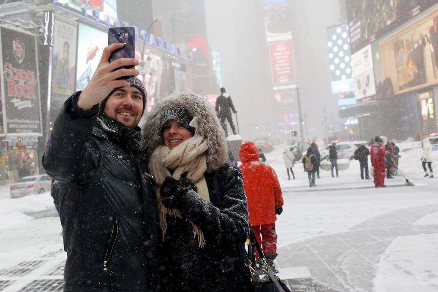 A couple takes a selfie during a snowstorm in the middle of Times Square in the heart of New York City. Impress your date with a spectacular view of the sunset from the best room at the Standard Hotel.