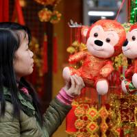 A woman looks at a decorative monkey at a shop selling red lanterns and Lunar New Year decorations in the old quarter of Hanoi on Saturday. Year of the Monkey inspires kung fu, predictions of fire, disease
