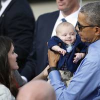President Barack Obama holds 3-month-old Charlie Allsup as he meets with the crowd before departing on Air Force One at Moffett Federal Airfield Thursday in Mountain View, California. Obama confident carbon pledge has 'legal footing' despite top court halt