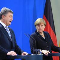 Angela Merkel, Germany's chancellor, looks on as Petro Poroshenko, Ukraine's president, speaks during a news conference at the Chancellery in Berlin on Monday. Poroshenko says Russia still sending troops, arms to east Ukraine