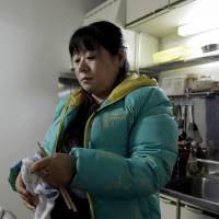 Chinese trainee Tang Xili wipes her chopsticks in a building housing a local labor union office and a shelter for Chinese trainees managed in Hashima, Gifu Prefecture, on Jan. 14. Forced labor allegations, abuses continue to dog Japan's foreign trainee program
