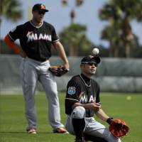 Ichiro Suzuki tosses a ball in the air as Miami teammate Giancarlo Stanton stands behind him on Tuesday. Ichiro reports to spring training
