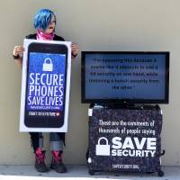 Activist Aki Rose holds a placard reading Secure Phones Saves Lives while protesting in front of the U.S. District Court in Riverside, California, on March 22. Security of iPhones the casualty in Apple's victory over the FBI