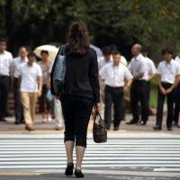 A woman waits to cross a road in the Tokyo’s Kasumigaseki area, which is the center of Japan’s government agencies. Although the government aims to increase the ratio of women in supervisory positions, they fill just 6.2 percent of junior management jobs in the bureaucracy. 'Womenomics' has to wait in line as tenure obstructs Abe's goal