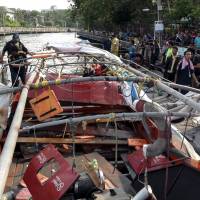 Rescue workers stand next to a river taxi engine that exploded in Bangkok on Saturday. More than 60 hospitalized as boat engine explodes in Bangkok; one Japanese injured