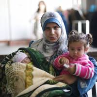 Syrian refugee Kholod, who got married 30 months ago in the camp, carries her daughters Fedaa’ (right) and Rima during a ceremony held by UNFPA maternal clinic marking the birth of 5,000 babies with no maternal deaths, at Al Zaatari refugee camp in the Jordanian city of Mafraq, near the border with Syria, Tuesday Rima is the 5,000th baby to be born safely in Zaatari camp clinics. Jordan camp of 79,000 Syrian refugees logs 5,000 births since 2013