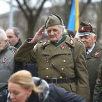 A man dressed in a pre-WWII Latvian military uniform salutes as veterans of the Latvian Legion, a force that was commanded by the German Nazi Waffen SS, and their sympathizers walk to the Monument of Freedom in Riga Wednesday to commemorate a key 1944 battle in their ultimately failed attempt to stem a Soviet advance. Jewish groups, Moscow and some in Latvia's ethnic-Russian community see the parade as glorifying Nazism because the Legion, founded in 1943, was commanded by Germany's Waffen SS, the armed wing of the Nazi party's Schutzstaffel SS (Protective Squadron). Latvia WWII vets who fought for Waffen SS stage contentious parade