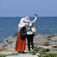 Visitors to the coastline take pictures facing the Indian Ocean a day after a 7.8-magnitude earthquake struck far out at sea in Padang, West Sumatra province, Indonesia on Wednesday. Indonesia's early tsunami warning buoys down when big quake hit