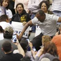 A member of the audience (right) stomps on a protester as Republican Presidential candidate Donald Trump speaks during a campaign event in Tucson, Arizona, Saturday. Videos may not lie but Trump denies 'spirited' campaign chief grabbed protester