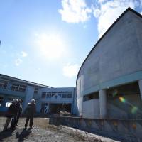 Participants in a dark tourism tour check out vacant Ukedo Elementary School in the abandoned town of Namie, Fukushima Prefecture, in early February. As the fifth anniversary of the 2011 calamity approaches, a growing number of visitors are taking part in Fukushima-related tours. 'Dark tourism' grows at 3/11 sites