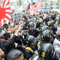 Riot police try to form a barrier between members of the ultraconservative anti-Korean Zaitokukai organization and a group of counterprotesters in Tokyo's Shinjuku Ward in May 2013. Japan's first-ever hate speech probe finds rallies are fewer but still a problem