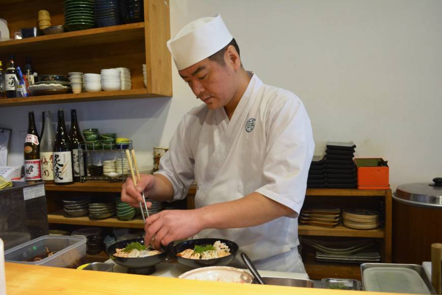 Fujimoto Seafood stack: Chef Futoshi Fujimoto puts the final touches on his version of the kaisendon, a generous serving of fresh sashimi on a bed of rice. | J.J. O'DONOGHUE