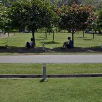 Protection from the sun: People sit in the shade on a hot day at a public park in Yangon on March 17. Plants won't boost warming as much as feared