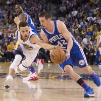 Golden State's Stephen Curry (left) tries to steal the ball from Philadelphia's T.J. McConnell on Sunday. Warriors down Sixers to stay on record pace