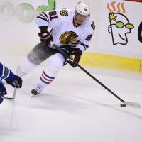 Chicago's Marian Hossa controls the puck as Vancouver's Ben Hutton defends during the Blackhawks' 3-2 win on Sunday. Blackhawks clinch spot in playoffs