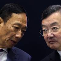Terry Gou, chairman of Foxconn Technology Group (left), exchanges words with Kozo Takahashi, president of Sharp Corp., at a news conference in Osaka on April 2. Sharp mulls cutting another 1,000 jobs