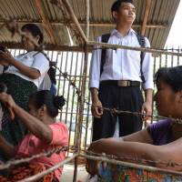 In this photograph taken on Friday, Bhone Hlaing Oo (second right, standing) waits for the release of his father, Htin Kyaw (no relation to Myanmar president with the same name), a political prisoner sentenced to 10 years in jail at Insein prison in Yangon. Myanmar drops charges against nearly 200 political activists: police