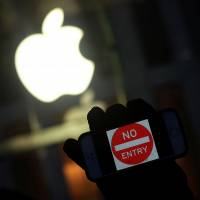 An anti-government protester holds up an iPhone reading “no entry,” during a demonstration near the Apple store in New York on Feb. 23. Uncle Sam keeps pressuring Apple for iPhone keys