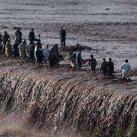 Pakistani residents cross a flooded street following heavy rain on the outskirts of Peshawar on Monday. At least 53 people were killed and 60 injured after heavy rain across northwest Pakistan and areas of Kashmir caused landslides and the roofs of dozens of homes to collapse, officials said. Rescuers race to reach rain-trapped thousands in Pakistan as deaths rise to 61