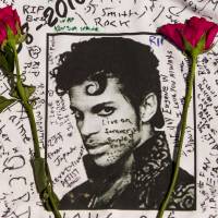 Flowers lie on a Prince T-shirt signed by fans of the musician at a makeshift memorial outside Apollo Theatre in New York on Friday. Police find no signs of trauma or suicide in Prince's death